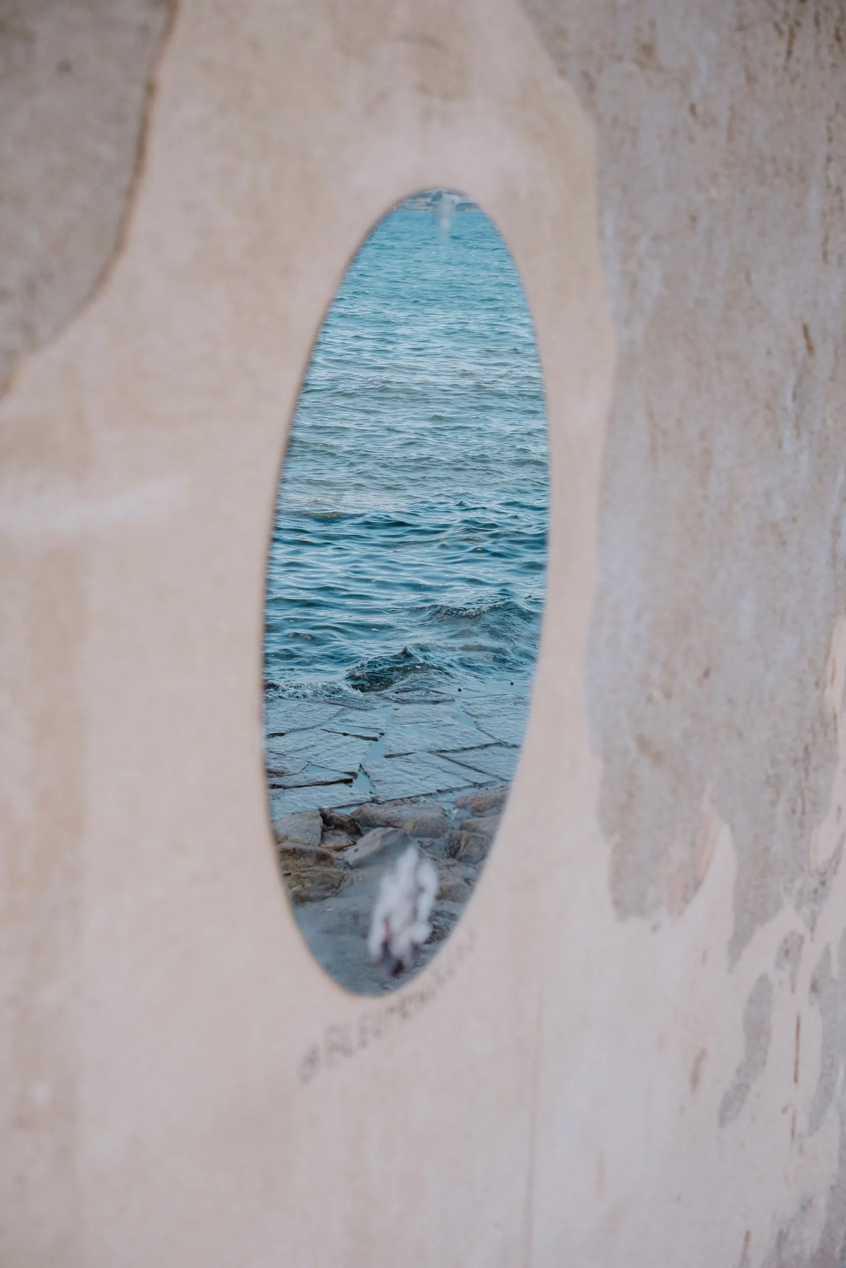 Une ouverture ovale dans un vieux mur, ouverte sur la mer