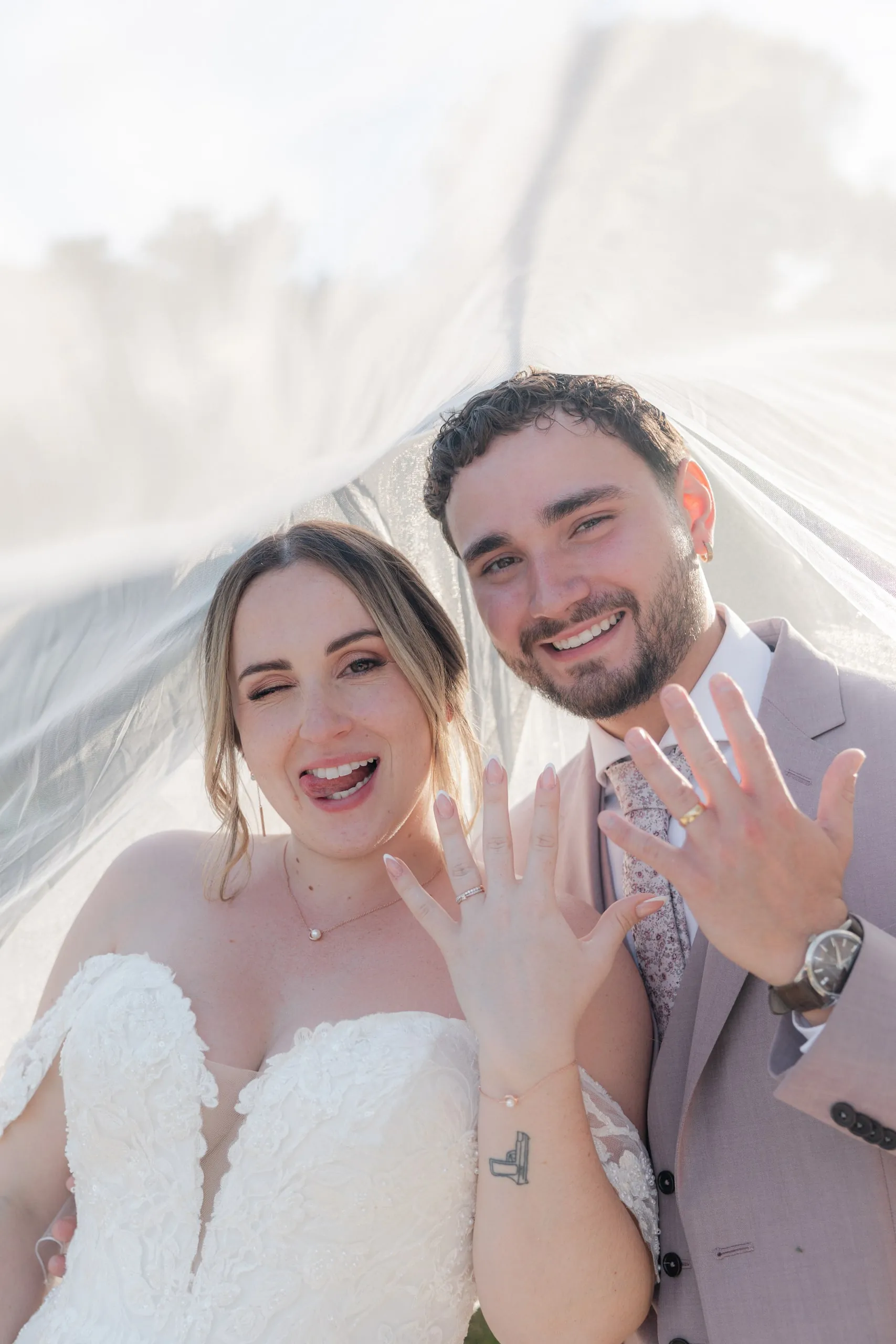 Lorena et Hugo sous le voile, montrant leurs alliances en riant