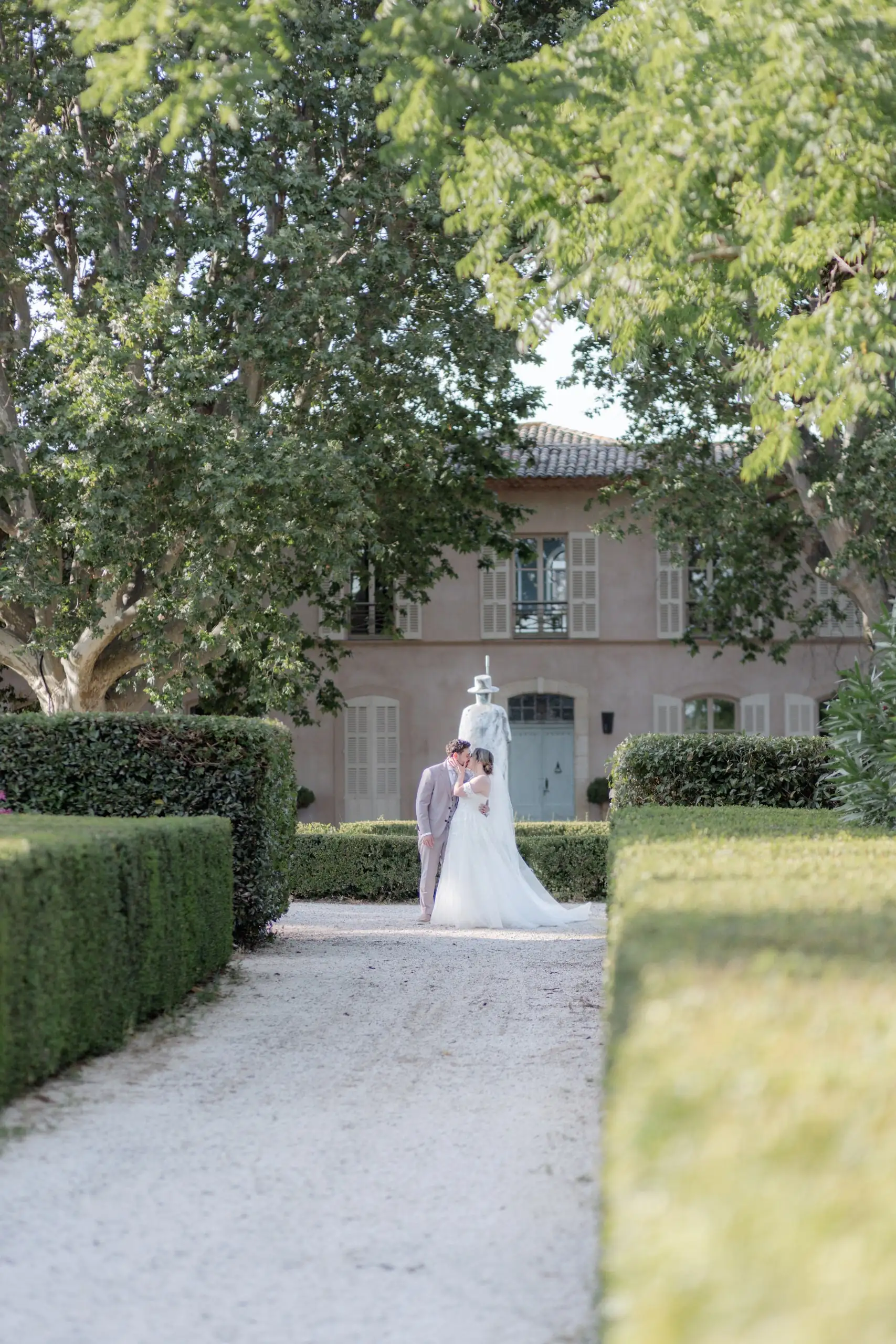 La mariée remonte l'allée de gravier vers la bastide aux volets gris