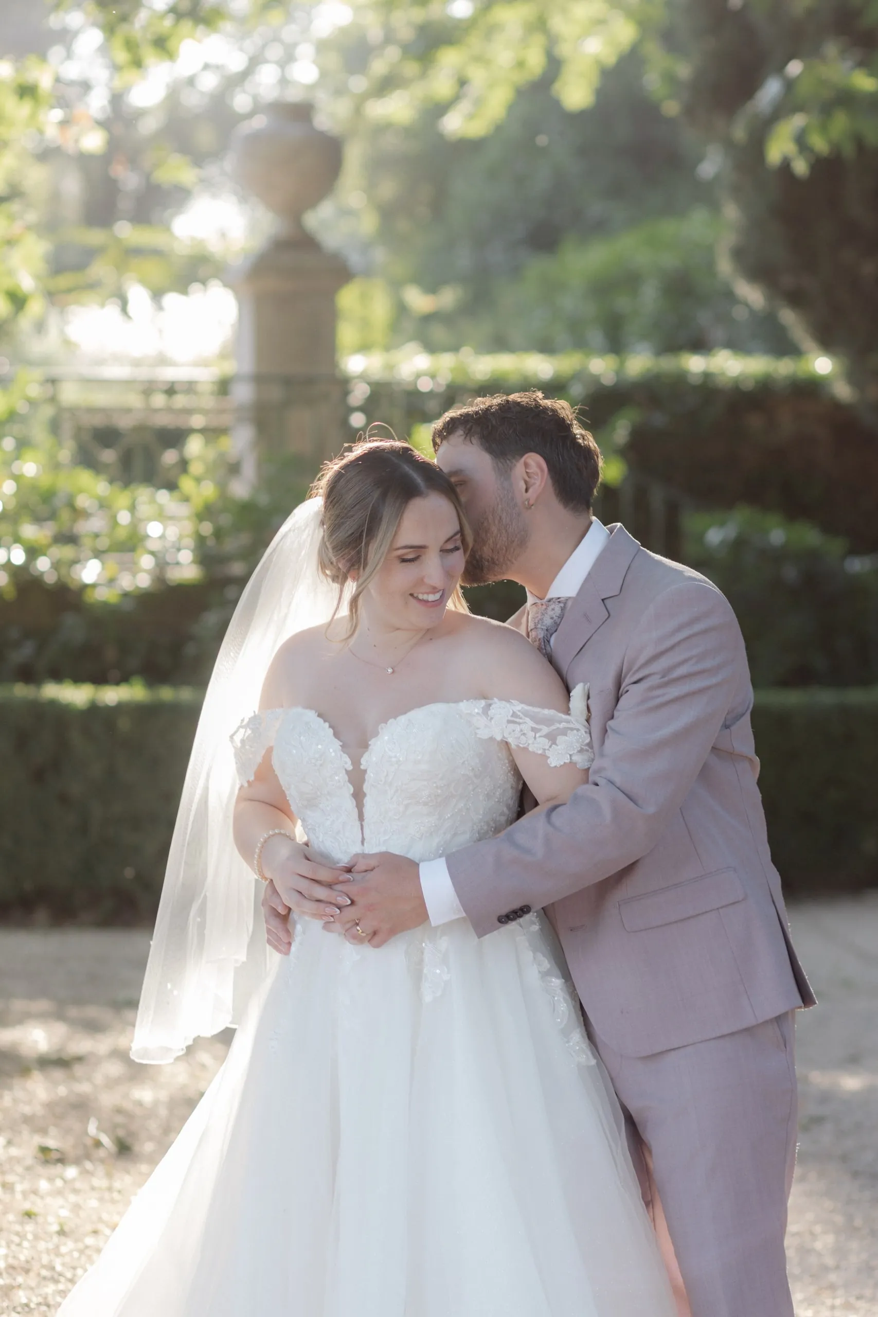 Le marié embrasse le front de la mariée dans le parc